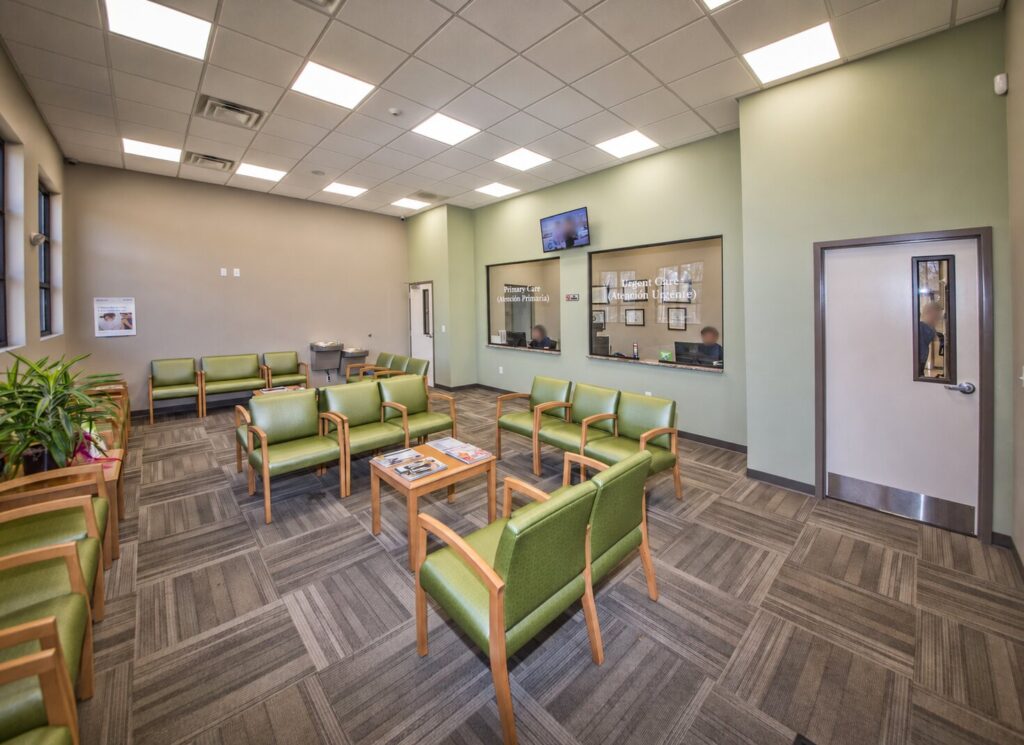 Bright patient waiting room at Charlotte Weight Loss and Wellness Clinic with green seating and reception windows.