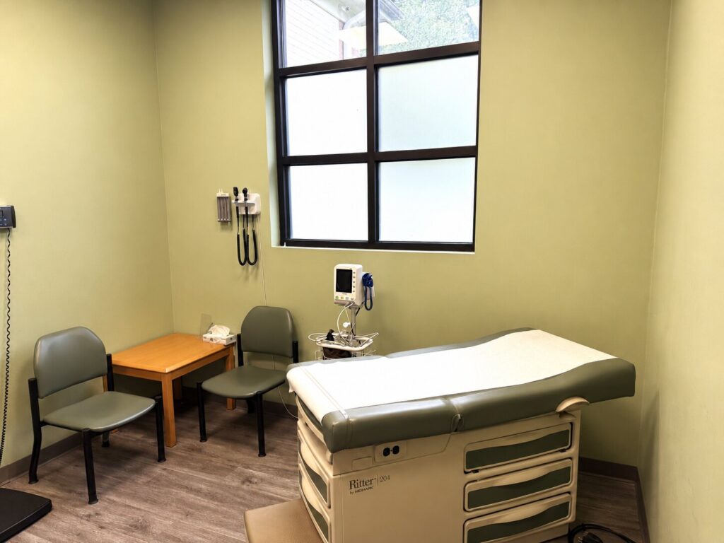 Private exam room at Charlotte Weight Loss and Wellness Clinic with an exam table and clinical monitoring equipment.